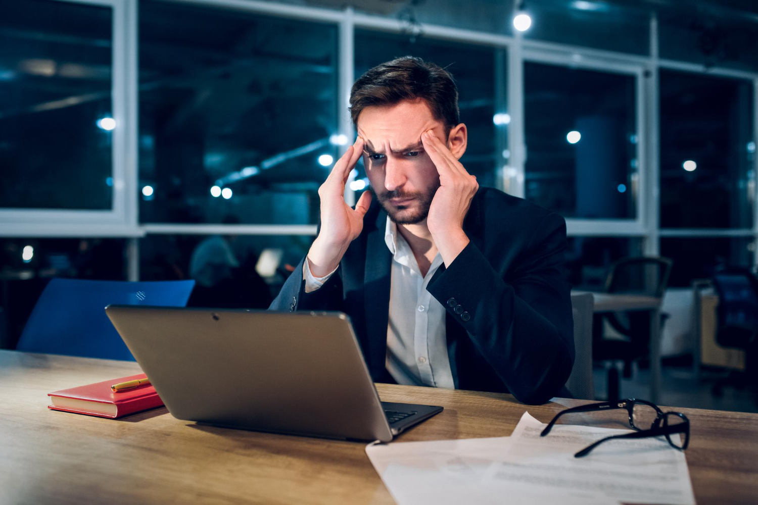 empresario de camisa e terno com cara de preocipado olhando para computador